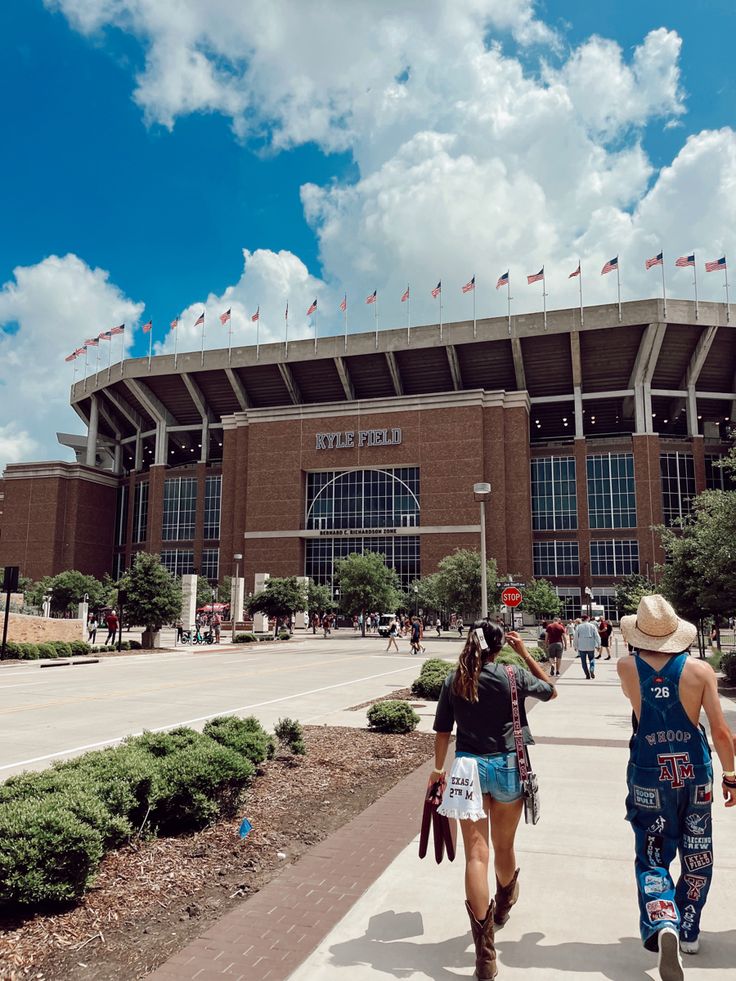 two women walking in front of a stadium