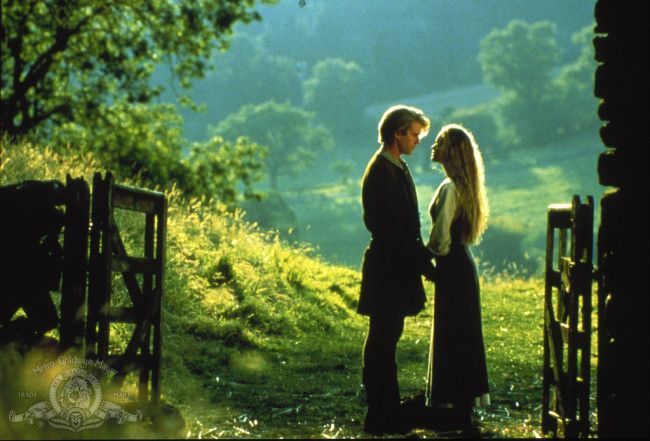 two people standing next to each other in front of a tree and grass covered field