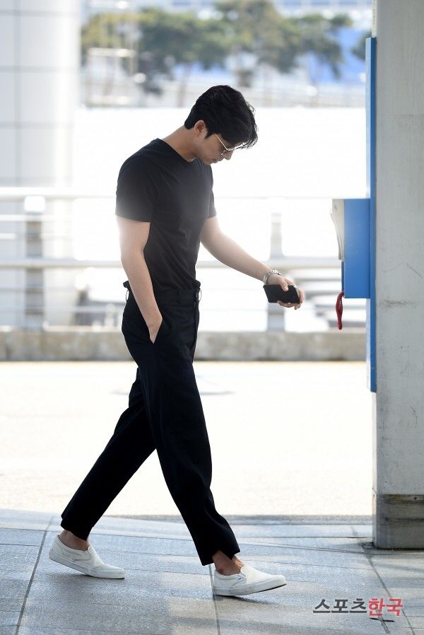 a man in black shirt and pants walking on sidewalk