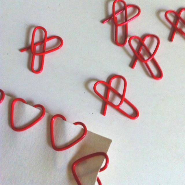 some red paper clips sitting on top of a white table