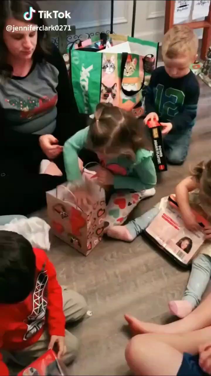 a group of children sitting on the floor opening presents