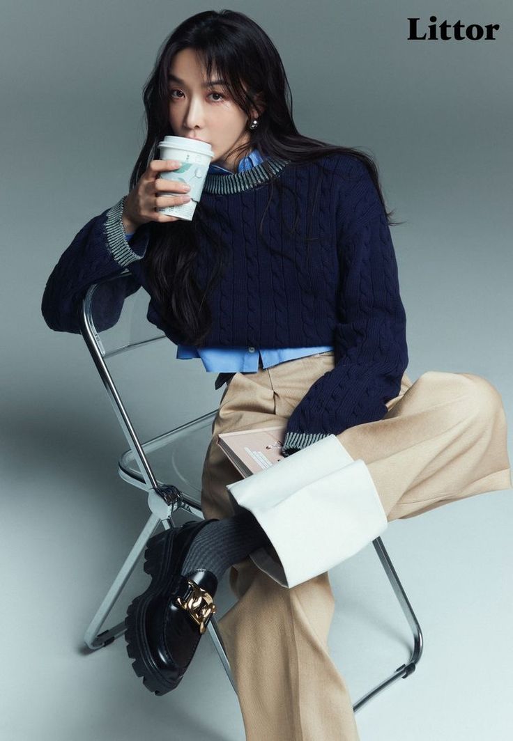 a woman sitting in a chair drinking from a cup