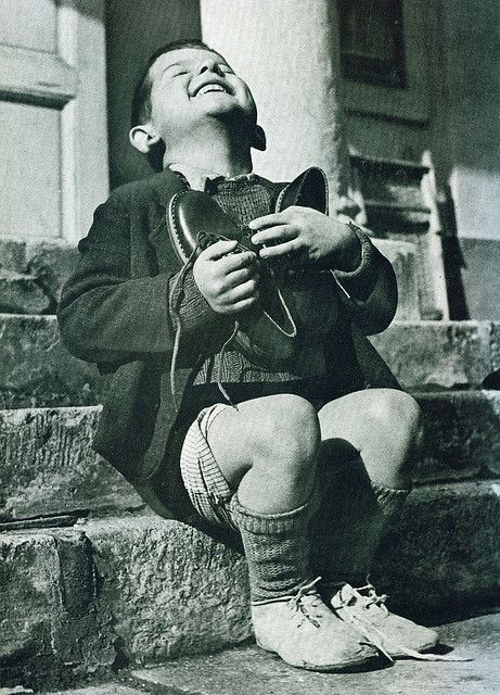 an old black and white photo of a young boy sitting on steps with his eyes closed