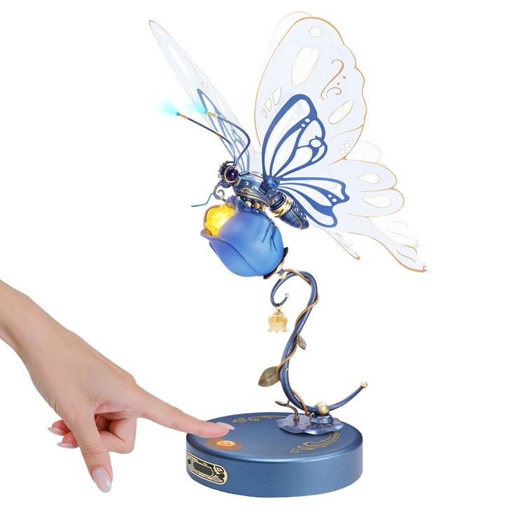 a hand is pointing at a blue and gold figurine with a butterfly on it