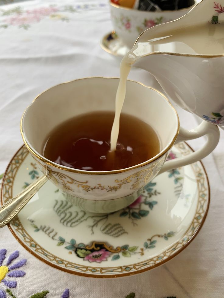 tea being poured into a cup on top of a saucer