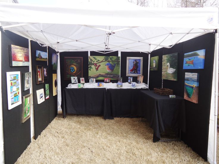 there are many paintings on display under the tent