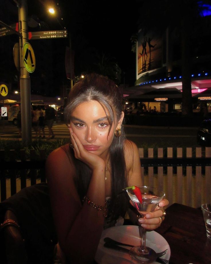 a woman sitting at a table with a martini in her hand