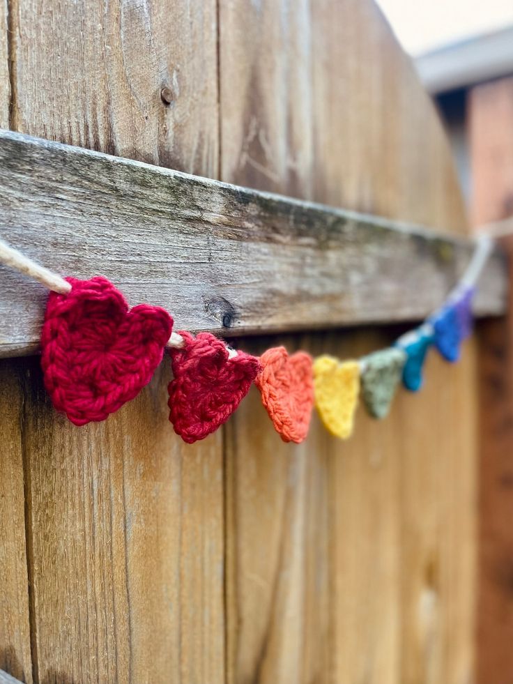 crocheted hearts hanging on a wooden fence