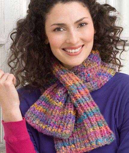 a woman with curly hair wearing a multicolored knitted scarf and smiling at the camera