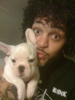 a man holding a small white dog in his lap and looking at the camera with an intense look on his face