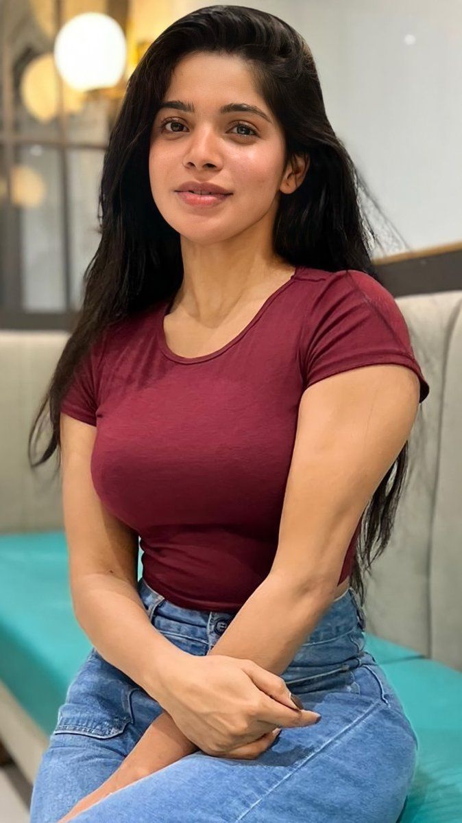 a woman sitting on top of a couch next to a blue chair and looking at the camera