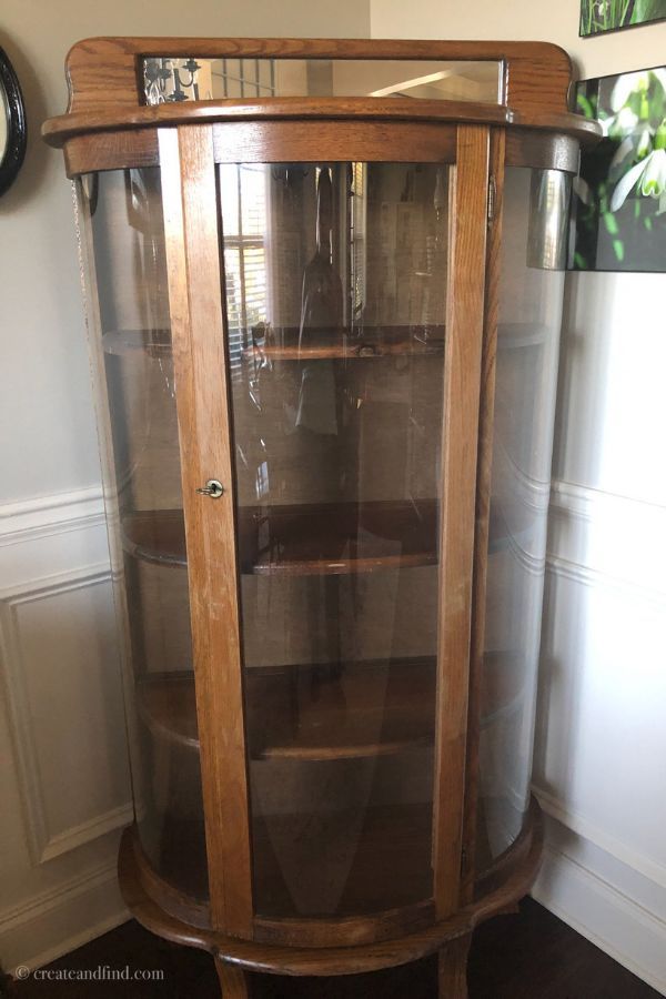 a wooden corner cabinet with glass doors