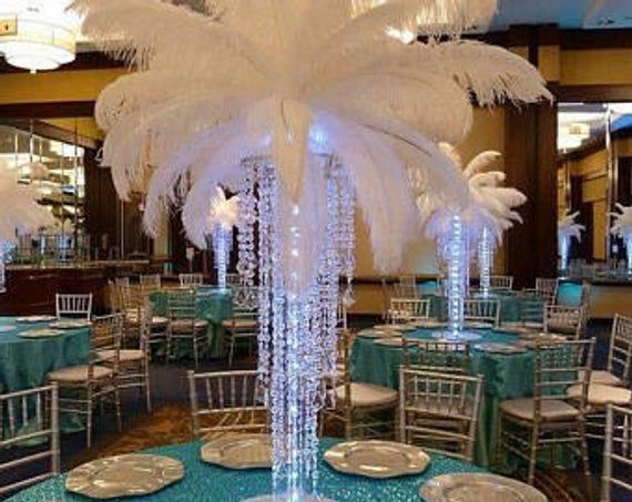 the centerpieces are decorated with white feathers and blue tablecloths, along with silver plates