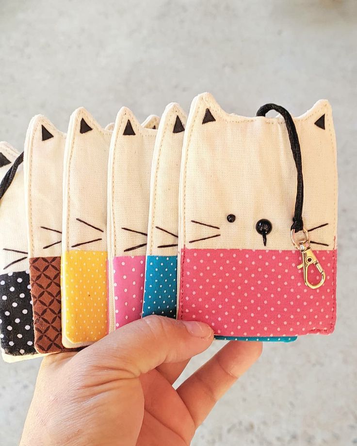 a hand holding four small cat purses