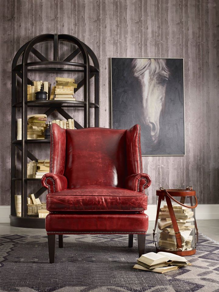 a red leather chair sitting in front of a book shelf with books on top of it