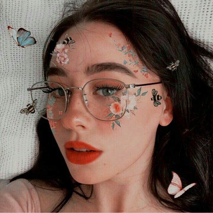 a woman wearing glasses with butterflies painted on her face and eyeliners in the shape of flowers