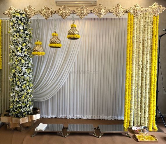 the stage is decorated with yellow flowers and white drapes, hanging from gold chandeliers