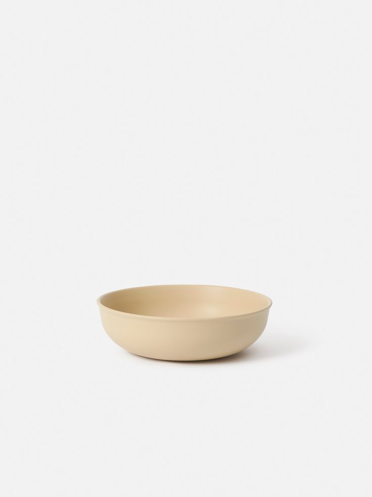 a white bowl sitting on top of a white table next to a black object in the background