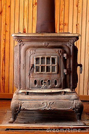 an old fashioned stove in front of a wood paneled wall stock photo - image