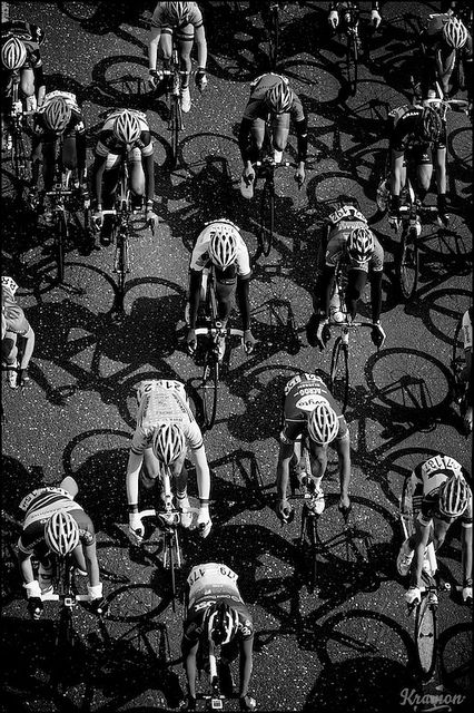 black and white photograph of cyclists riding on the same bike path as they head down the street