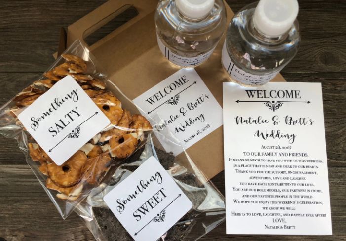 some cookies are sitting in a box with welcome tags on them and two bottles of water