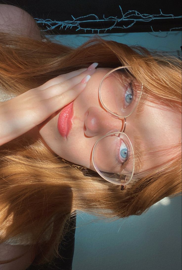 a woman with long red hair and glasses