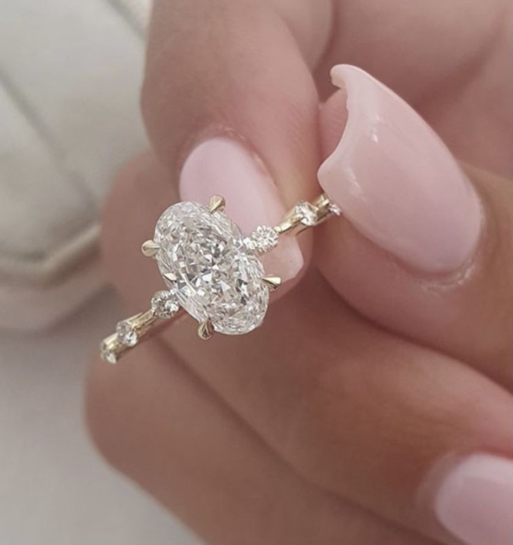 a woman's hand holding a ring with a flower on it and a diamond in the middle