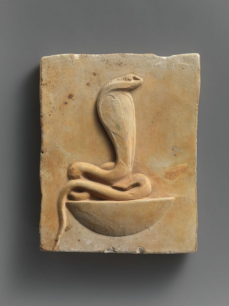 a stone block with an image of a snake on it's side and a bowl in the middle