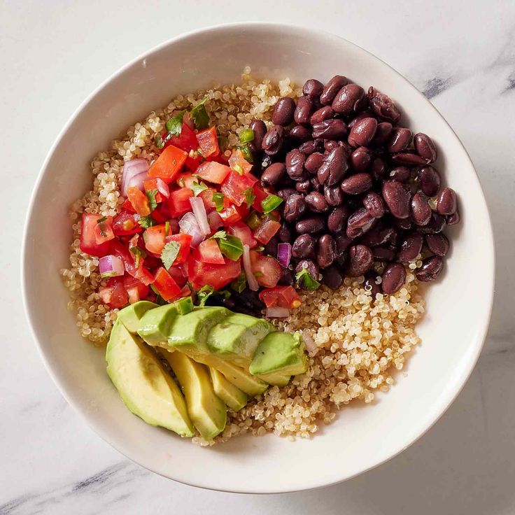 a white bowl filled with beans, avocado and rice