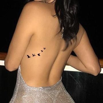 the back of a woman's body with birds on it