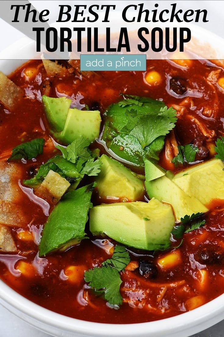 the best chicken tortilla soup with avocado and cilantro in a white bowl