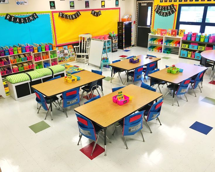 an empty classroom with desks and chairs in front of the wall that has colorful decorations on it