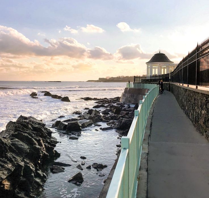 a person walking along the edge of a walkway next to the ocean