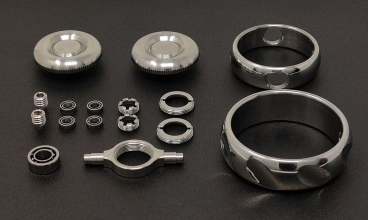 an assortment of metal parts are displayed on a black surface with spacers and screws