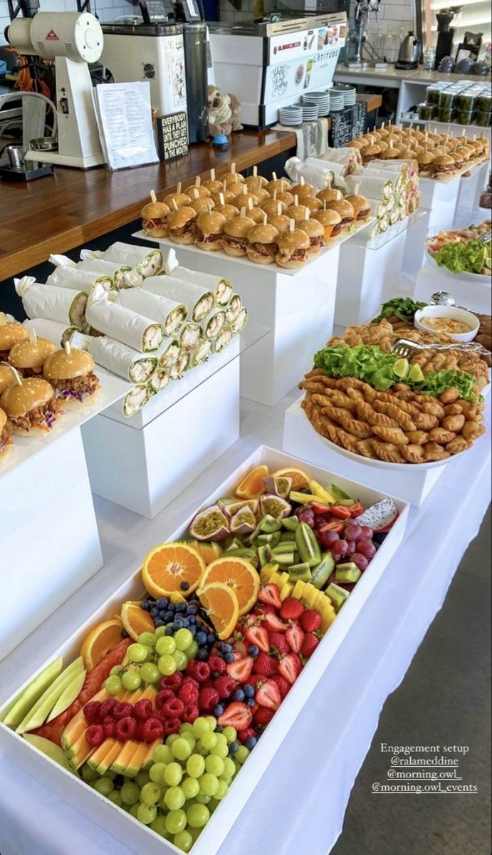 many different types of food are on display in white trays at a buffet table