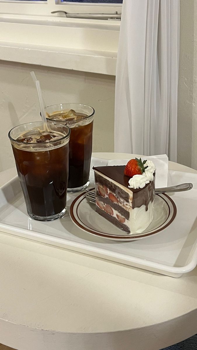 there is a piece of cake and two drinks on the tray