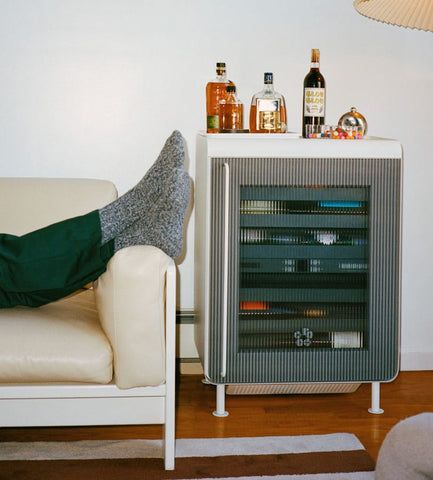 a person sitting on a couch in front of a cabinet with liquor bottles behind them