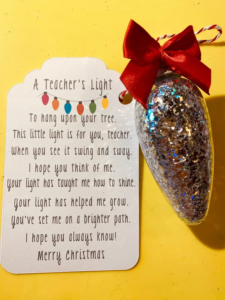 a teacher's light ornament next to a card with a red bow