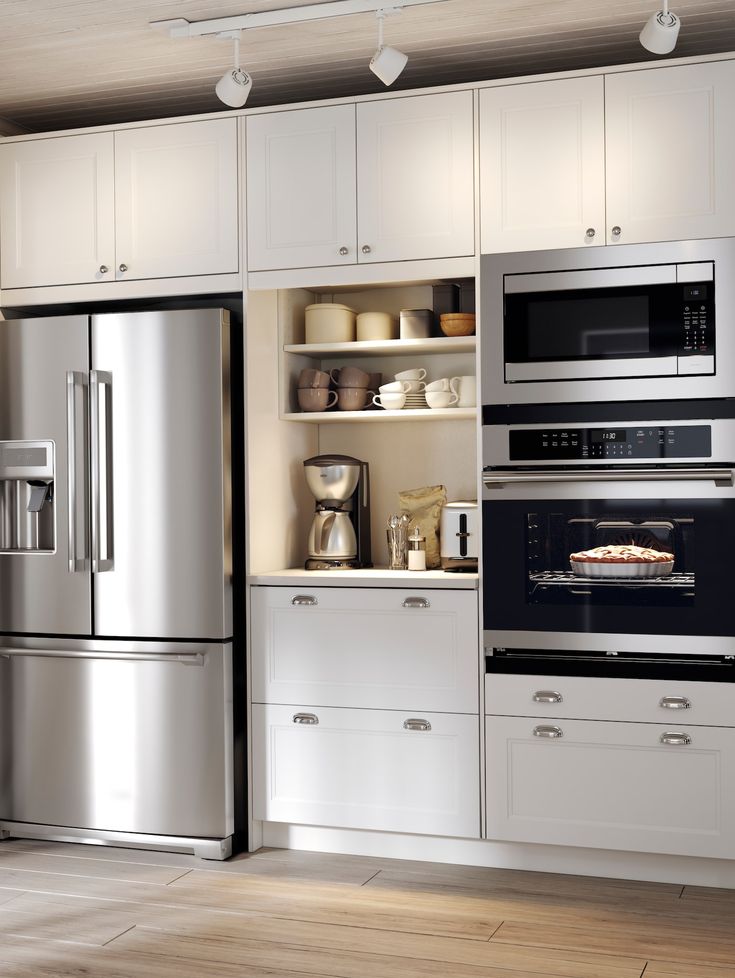 a modern kitchen with stainless steel appliances and white cupboards, along with wood flooring