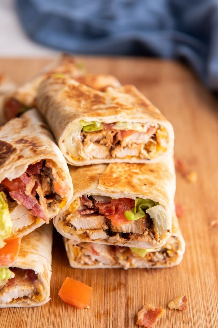 three burritos cut in half on a cutting board