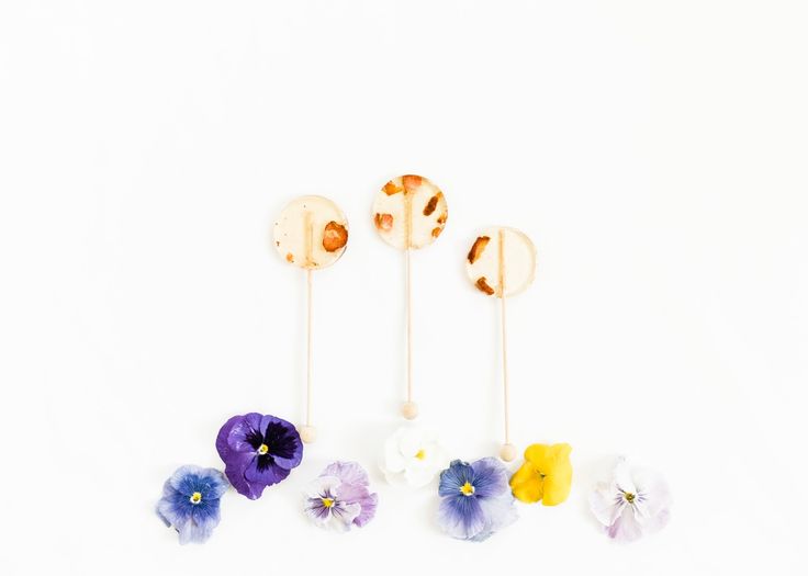 three lollipops with flowers on them sitting next to each other in front of a white background