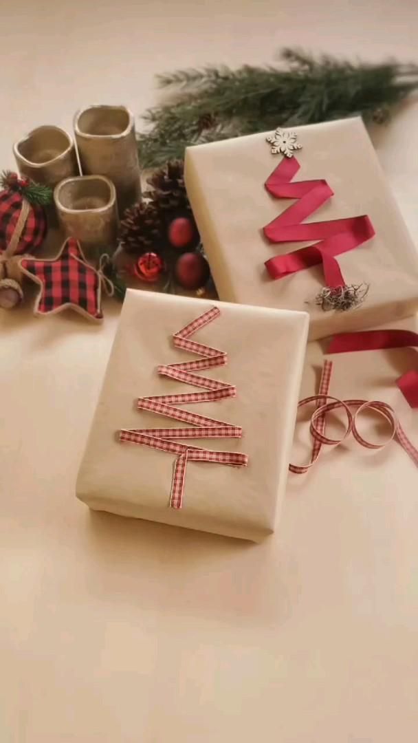 two wrapped presents sitting on top of a table next to christmas decorations and ribbon tied around them