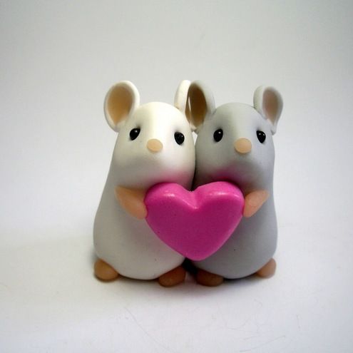 two white mice holding a pink heart shaped object