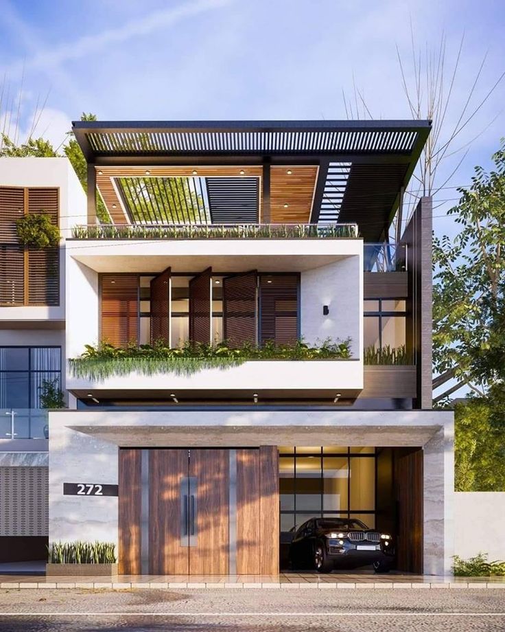 a car is parked in front of a building with plants on the balconies