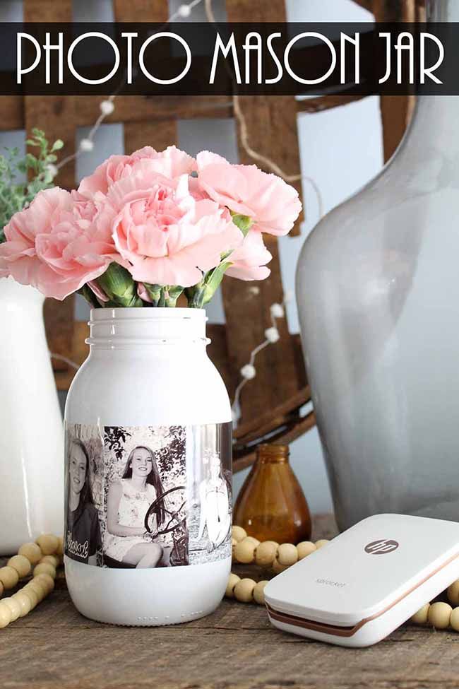 a vase with pink flowers sitting on top of a table next to a cell phone