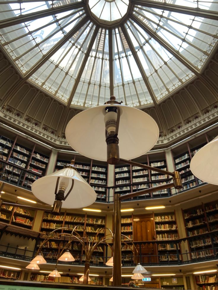 the inside of a library with several lamps and bookshelves on each side of the ceiling