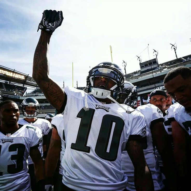 a football player holding his fist up in the air with other players standing behind him