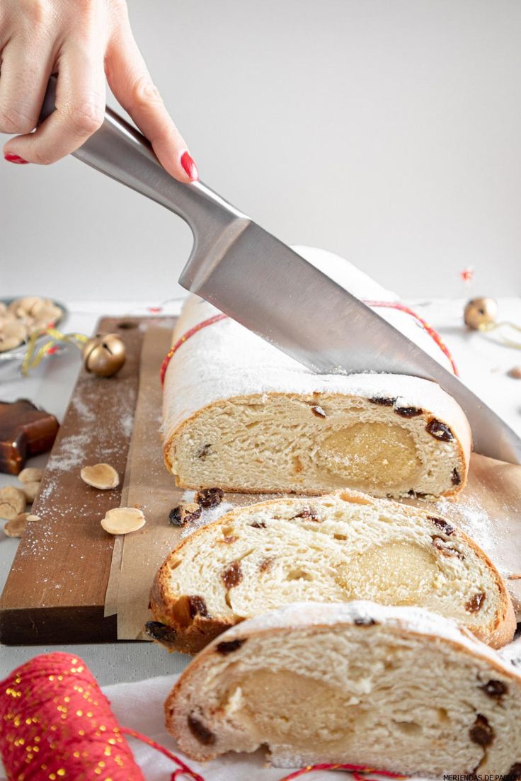 someone is cutting into a loaf of bread on a wooden board with the words christmas stollen