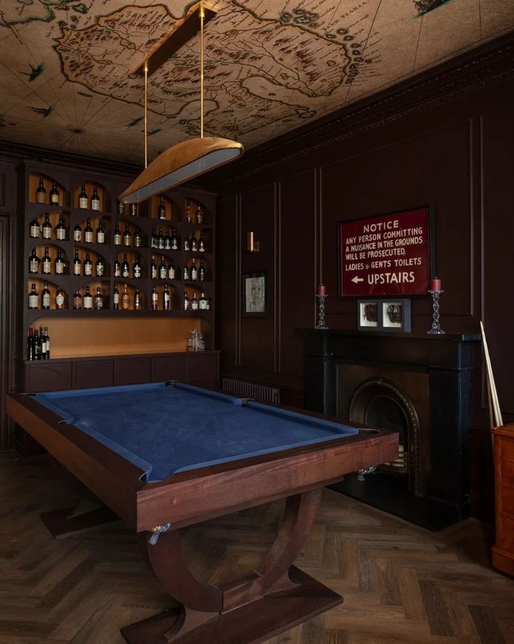 a pool table is in the middle of a room with shelves on the wall and a fireplace