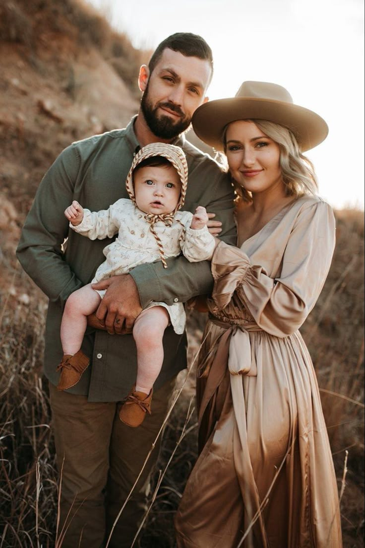 a man and woman holding a baby in their arms while standing next to each other